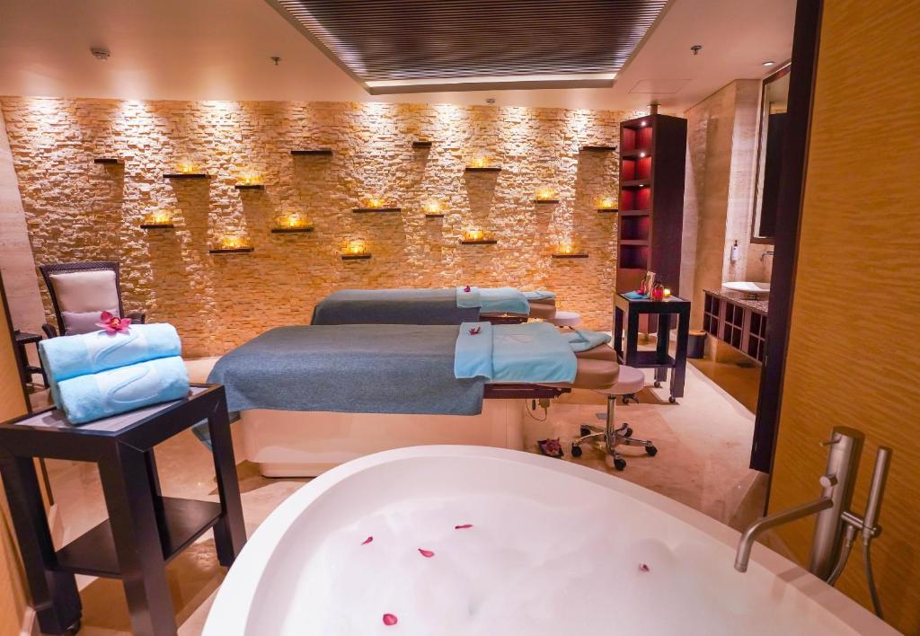 Mūsdienīgs spa interjers ar divām masāžas gultām, relaksējošu apgaismojumu un vannu, kas piepildīta ar ziedlapiņām. Ideāla vide atpūtai un pašapkalpošanās procedūrām.