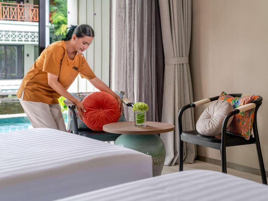 Viesnīcas Grand Mercure Khao Lak Bangsak darbinieks sakārto spilvenus numurā.