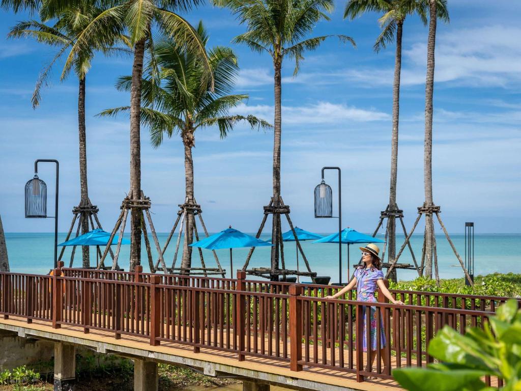 Sieviete, kas stāv uz koka tilta starp palmām pie Grand Mercure Khao Lak Bangsak