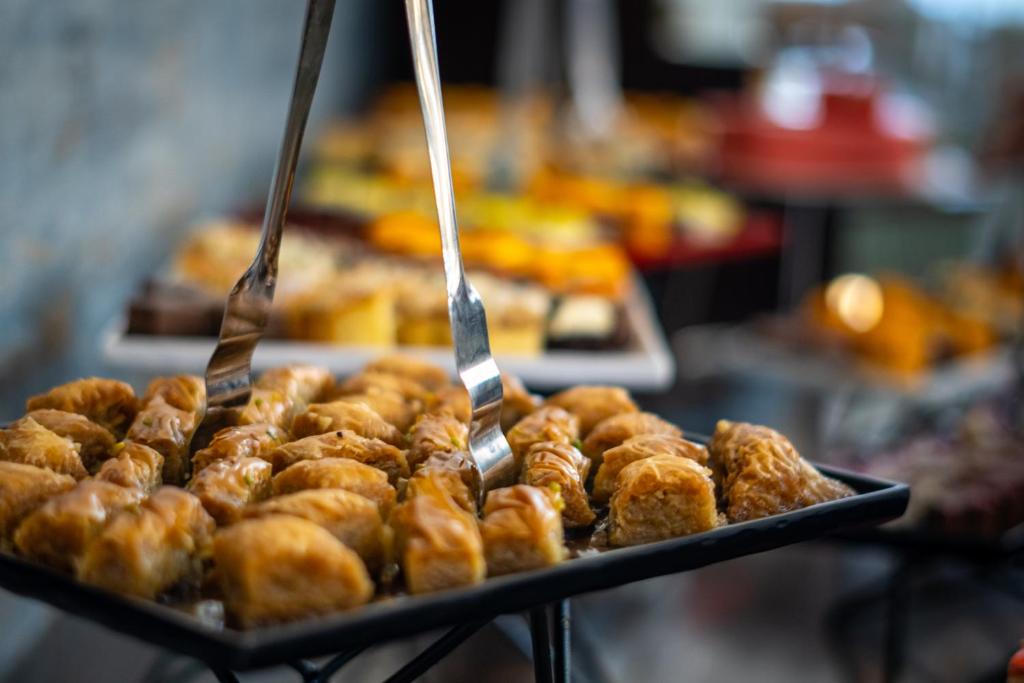 Baklažāni un saldumi uz galda, ar metāla dakšām, kas izmanto, lai paņemtu desertus. Saldumi ir bagāti ar riekstiem un medu.