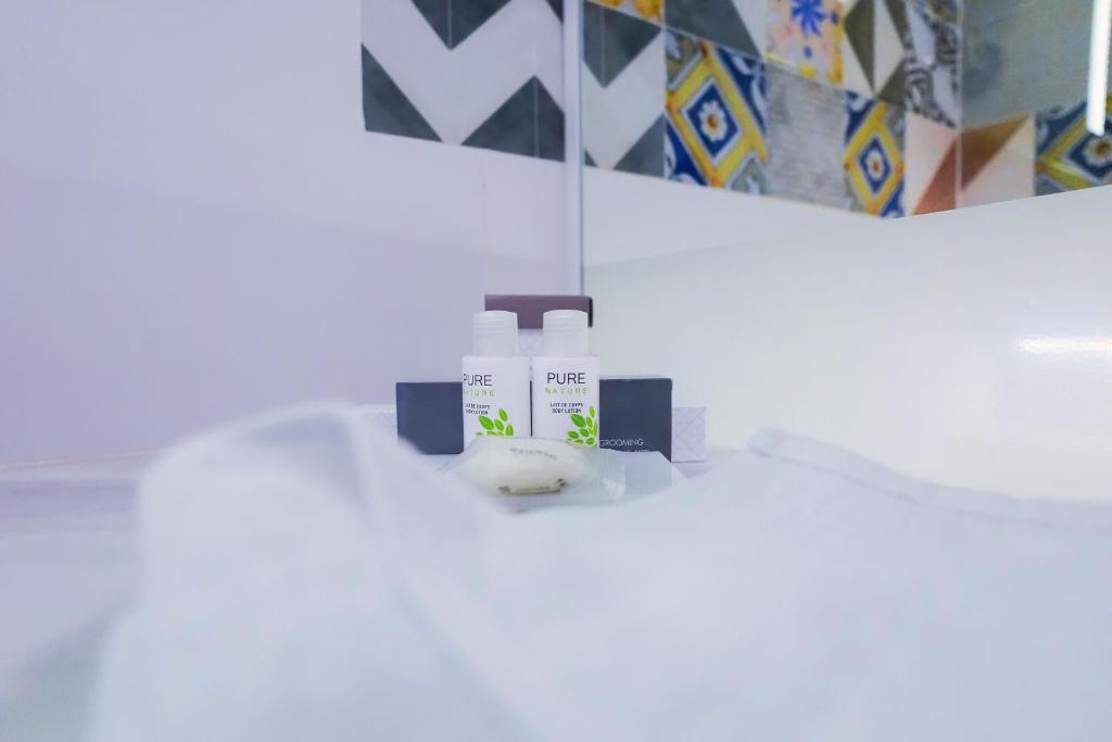 Kosmētikas produktu kolekcija uz balta galda, ieskaitot šampūnu un kondicionieri ar dabīgu sastāvu, fons ar krāsainiem flīzēm.