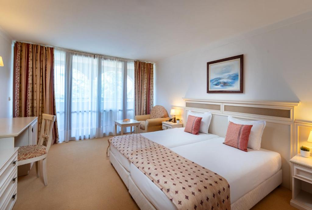 Mūsdienīgs viesnīcas numurs ar divām gultām, rakstāmgaldu un ērtu atpūtas zonu. Lieli logi nodrošina dabīgu apgaismojumu, radot patīkamu atmosfēru.