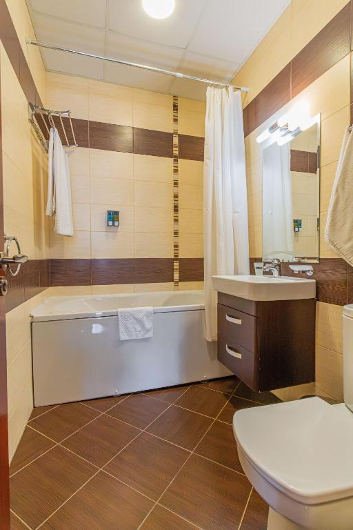 Mūsdienīga vannas istaba ar vannu, dušas aizkariem un modernu izkārtojumu. Telpa ir gaiša un ērta, ar izsmalcinātu flīžu apdari.