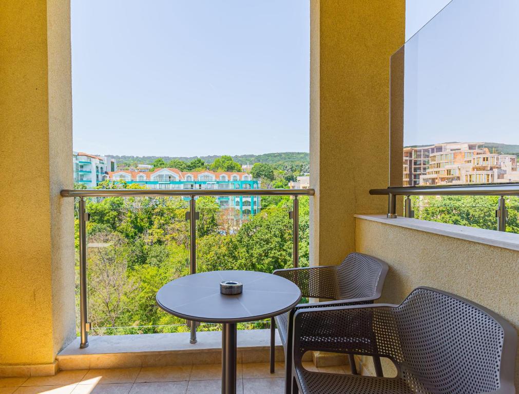 Balkons ar skatu uz zaļo dabu, aprīkots ar galdu un krēsliem, ideāls vieta relaksācijai.