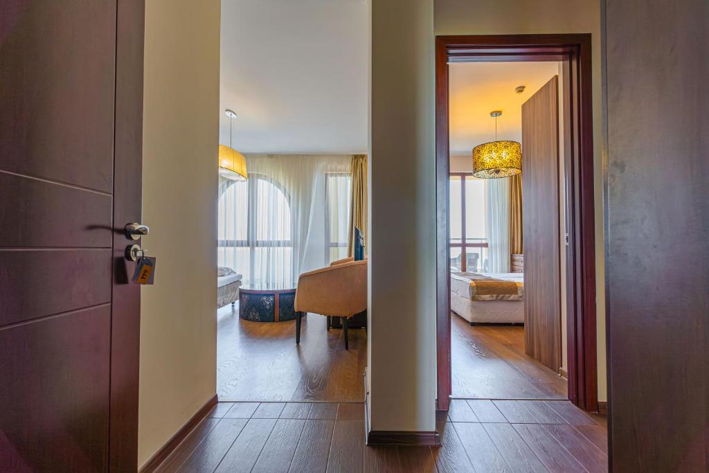 Mūsdienīga interjera skats no koridora, kas vēršas uz viesistabu un guļamistabu, ar dabīgu apgaismojumu un elegantu apdari.