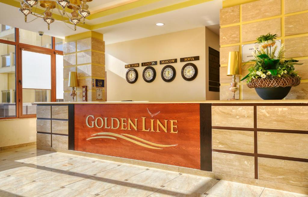 Recepcija viesnīcā "Golden Line" ar modernu dizainu, dekorēta ar ziedu kompozīciju un pulksteņiem dažādām pilsētām.