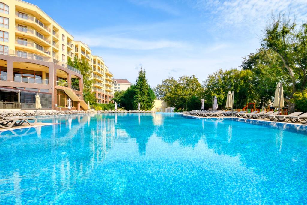 Liela, skaidra baseina aina ar sauļošanās krēsliem, apkārt esošām ēkām un zaļiem kokiem. Ideāla vieta atpūtai un relaksācijai.