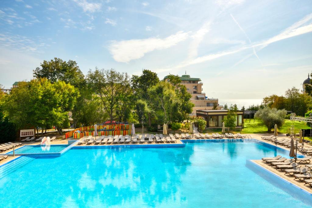 Vasaras atpūtas vieta ar lielu peldbaseinu un sauļošanās krēsliem, apzaļumots dārzs un viesnīca fona. Ideāla vieta relaksācijai un atpūtai.