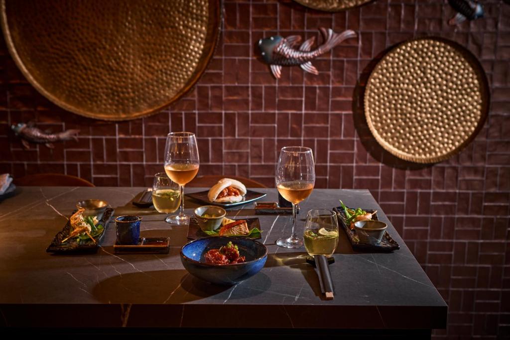 Elegants restorāna galda izkārtojums ar dažādiem ēdieniem, dzērieniem un dekoratīviem elementiem. Siltās krāsas un stilīga apdare rada patīkamu atmosfēru.