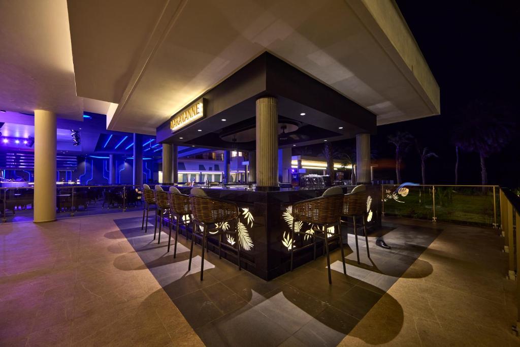 Moderns bārs ar elegantu apgaismojumu un krēslu rindu, kas izceļas nakts ainavā. Dizains apvieno mūsdienīgus elementus ar tropiskiem akcentiem.