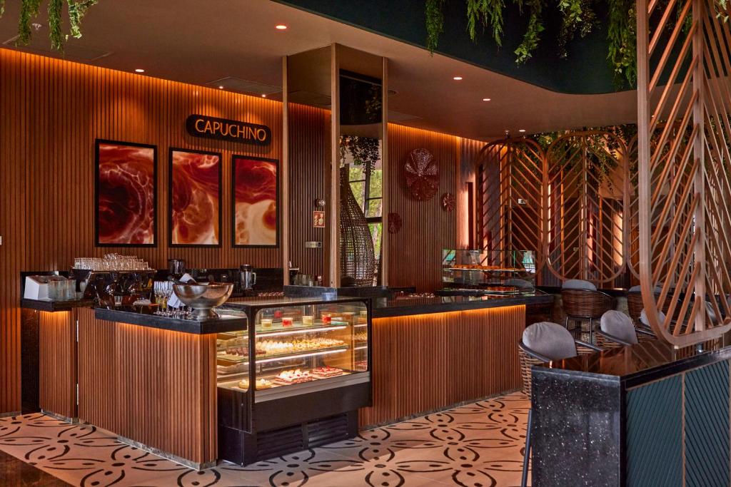 Moderns kafejnīcas interjers ar elegantu dizainu, kas ietver koka apdari un mākslinieciskas gleznas. Uzsvars uz gaismas un telpas harmoniju, piedāvājot patīkamu atmosfēru.