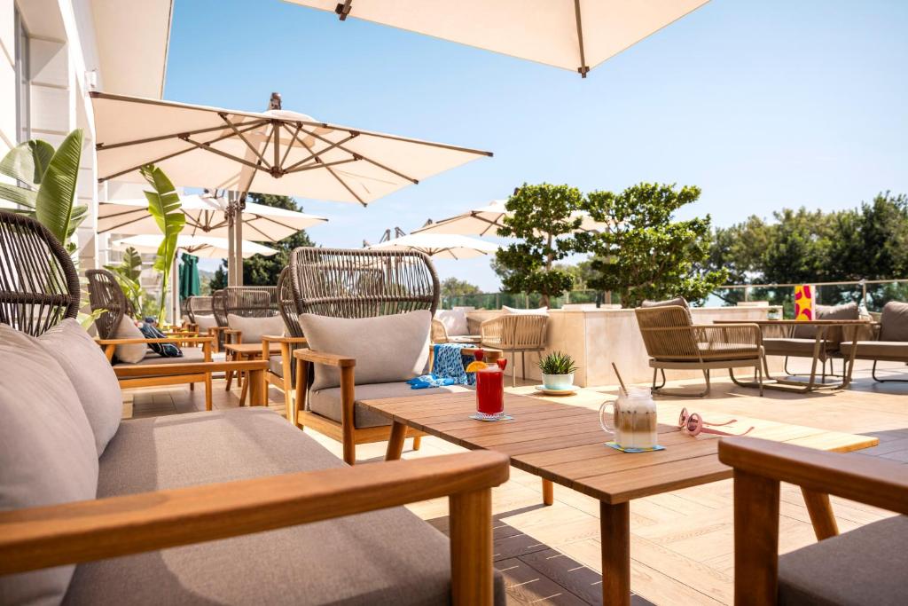 Sauļošanās vieta ar koka mēbelēm, saules parasoliem un dzērieniem uz galda, kas rada relaksējošu atmosfēru. Ideāla vieta atpūtai un izklaidei.