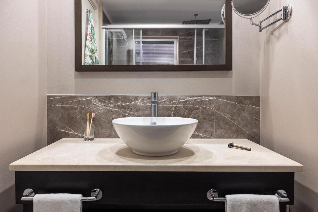 Mūsdienīgs vannasistabas interjers ar elegantu izlietni un spoguli, uz galda redzami zobu sukas un skūšanās piederumi.