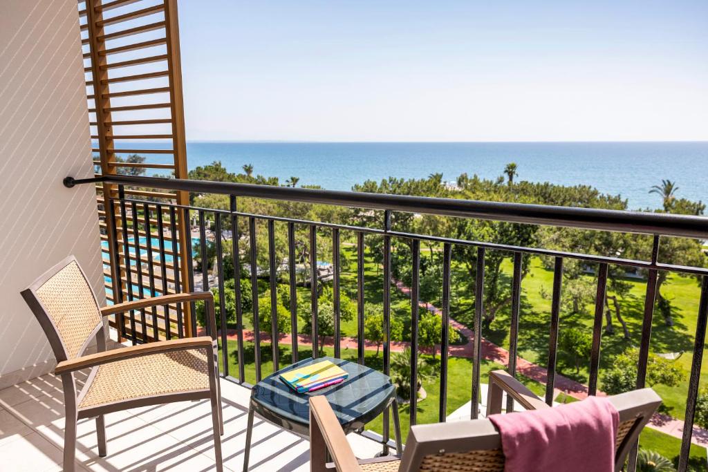 Balkons ar skatu uz jūru un zaļu ainavu, kurā ir ērtas krēsli un galdiņš ar grāmatām. Ideāla vieta relaksācijai un atpūtai.