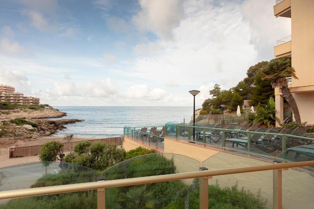 Jūras piekrastes skats ar baseinu un atpūtas zonu, kas ierāmēts ar zaļām augiem un mūsdienīgu arhitektūru. Ideāla vieta atpūtai un relaksācijai pie jūras.