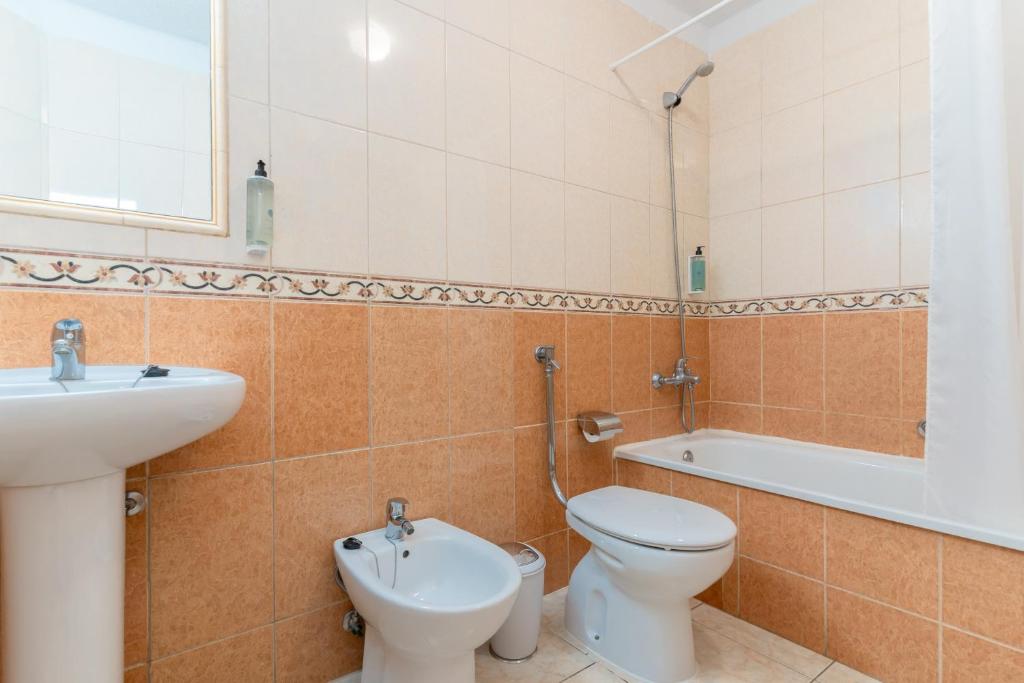 Vannas istaba ar dušu, vannu un sanitārajiem izstrādājumiem, kas izstrādāti vienkāršā un funkcionālā stilā. Sienas ir apšūtas ar flīzēm, kas piešķir telpai siltu un tīru izskatu.