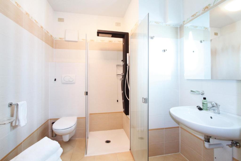 Mūsdienīgs vannas istabas interjers ar dušu, izlietni un tualeti, kas nodrošina komfortu un funkcionalitāti. Gaiši toņi un tīra dizaina elementi rada patīkamu atmosfēru.