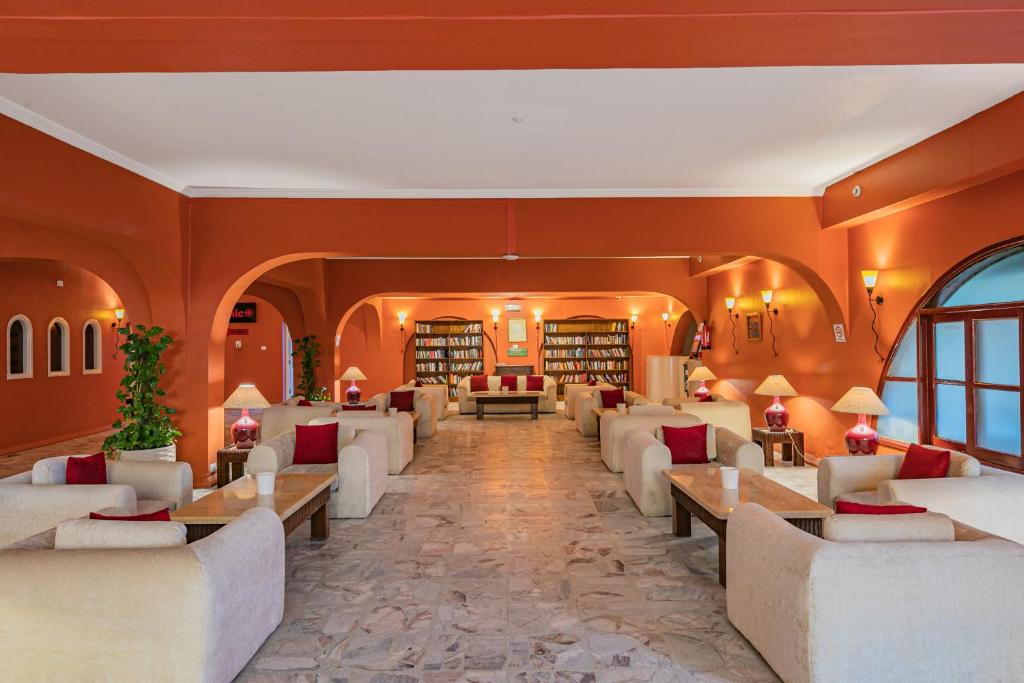 Mūsdienīgs un mājīgs lasītavu telpa ar sarkanu sienu, komfortablām dīvāniem un grāmatu plauktiem. Gaisma rada siltu atmosfēru, ideāli piemērota relaksācijai un lasīšanai.