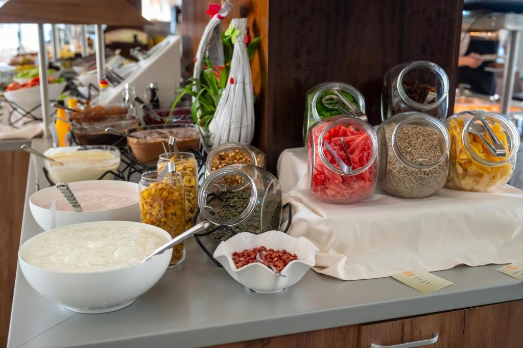 Bagātīgs brokastu bufete ar jogurtu, graudaugiem un dažādām augļu un riekstu sastāvdaļām stikla burkās.
