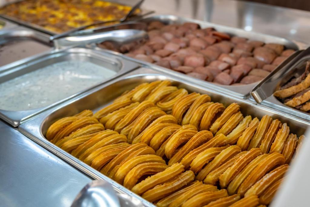 Saldējumus un dažādus ēdienus piedāvā bufetē, kurā redzami kraukšķīgi churros, krēmveida mērce un gaļas porcijas.