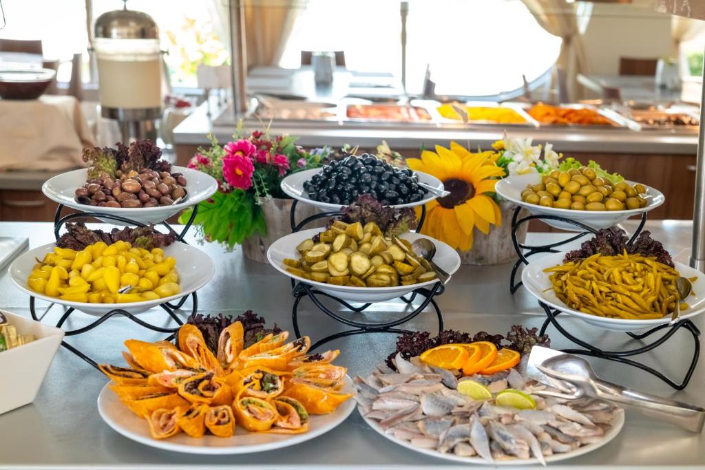 Dažādu uzkodu bufete ar olīvām, marinētiem dārzeņiem, jūras veltēm un krāsainām uzkodām. Uzkodu galdiņš dekorēts ar ziediem un piedāvā plašu izvēli.