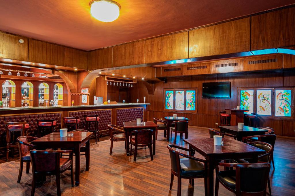 Eleganta bāra iekārtojums ar koka apdari un stikla mozaīkām, kas rada siltu un mājīgu atmosfēru. Bārā ir pieejami dažādi dzērieni un komfortabli sēdvietas.