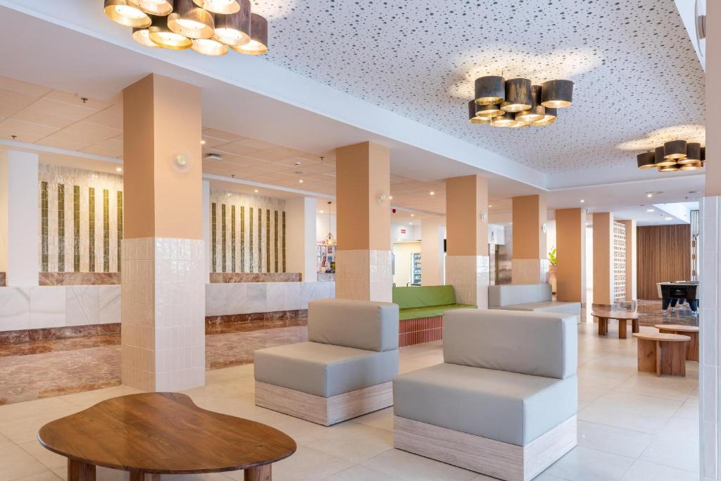 Mūsdienīgs viesnīcas interjers ar elegantiem mēbeļu elementiem un gaismas ķermeņiem, kas rada siltu atmosfēru. Plaša telpa ar atpūtas zonām un dekoratīvām sienām.