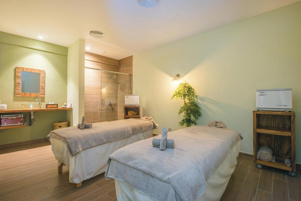 Mūsdienīga masāžas telpa ar divām gultām, dabīgām krāsām un relaksējošu atmosfēru. Telpā ir duša, spogulis un augu dekorācijas, kas veicina mieru un atpūtu.