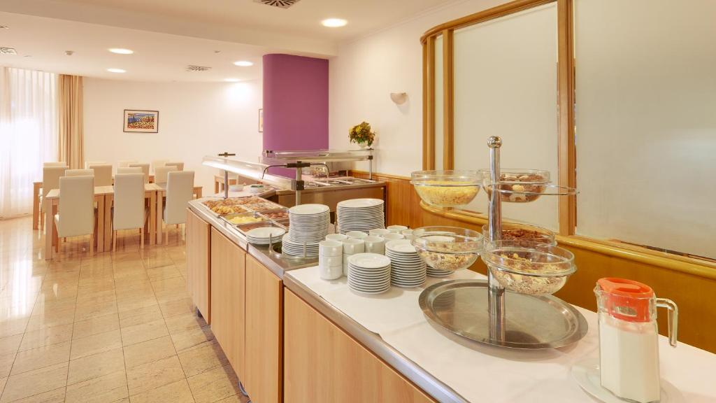 Brokastu galds ar dažādām ēdienu izvēlēm un galdiem, kas gaida viesus.