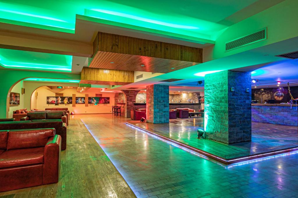 Mūsdienīgs bārs ar krāsainu apgaismojumu un sēdvietām, kas rada draudzīgu atmosfēru. Interjerā ir redzami akmens sienu elementi un koka detaļas.