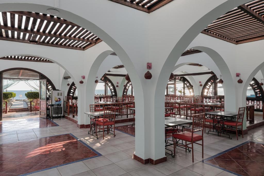 Restorāna interjers ar arku konstrukcijām, brīviem galdiem un krēsliem, kas vērsti uz jūru. Gaismas plūsma caur logiem rada patīkamu atmosfēru.