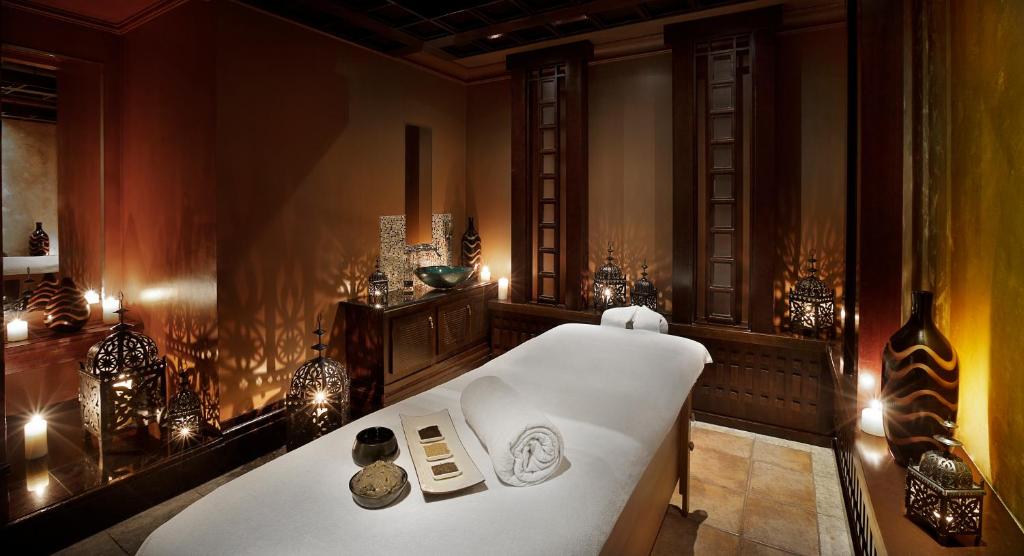 Mūsdienīgs spa interjers ar masāžas galdu, apgaismojumu no svečturiem un dekoratīvām lampām, radot relaksējošu atmosfēru.