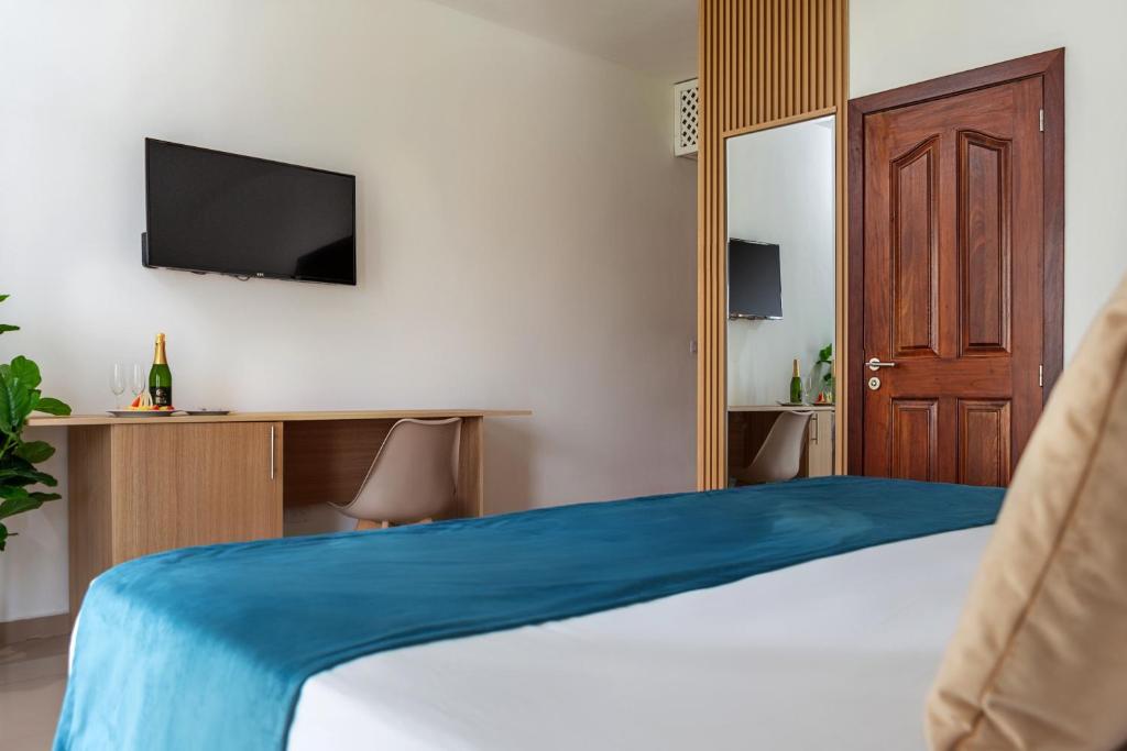 Mūsdienīga viesnīcas numura iekārtojums ar televizoru, rakstāmgaldu un ērtiem krēsliem, kā arī dekoratīvām augu kompozīcijām. Gaisīga atmosfēra un silta krāsu palete nodrošina komfortu un relaksāciju.