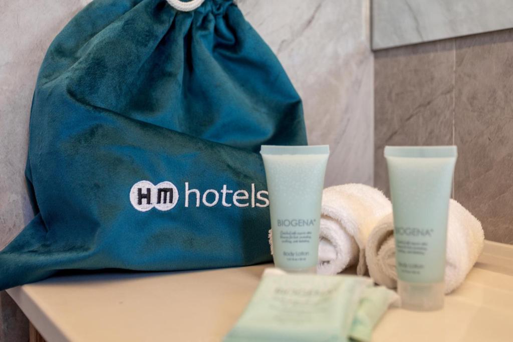 Viesnīcas HM zīmola maisiņš, kas satur ķermeņa losjonus un dvieļus, uzsver relaksācijas un komforta iespējas.
