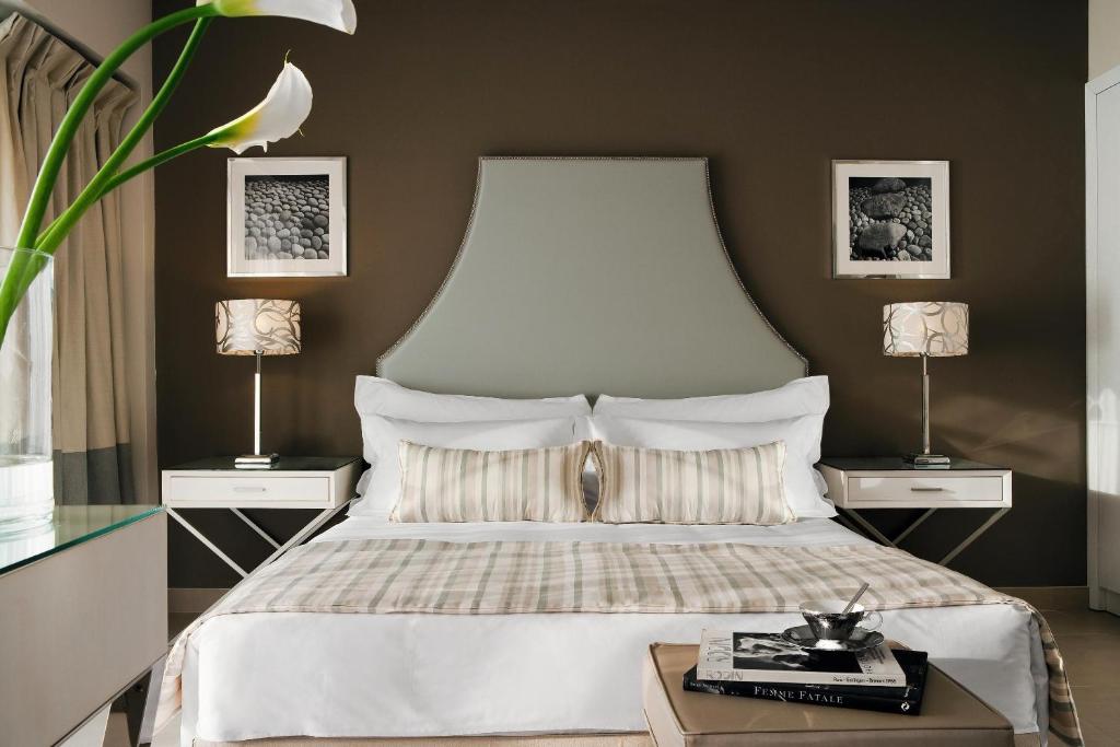 Mūsdienīgs guļamistabas interjers ar elegantu gultu, dekoratīviem spilveniem un stilīgām lampām, kas radīja patīkamu un relaksējošu atmosfēru. Klasiskais dizains papildināts ar mākslas darbiem uz sienām.