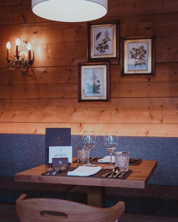 Eleganti izveidota restorāna galdiņa ar īpašu apgaismojumu, greznu galda piederumu komplektu un mākslas darbiem uz sienas.