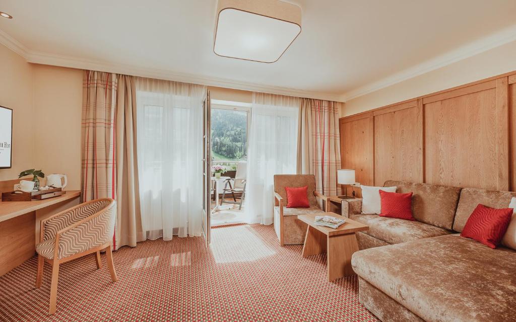 Mūsdienīgu viesnīcas numuru ar komfortablu dīvānu, ērtām krēsliem un balkonu, kas nodrošina skatu uz kalniem. Interjers ir gaišs un siltas krāsas, radot mājīgu atmosfēru.