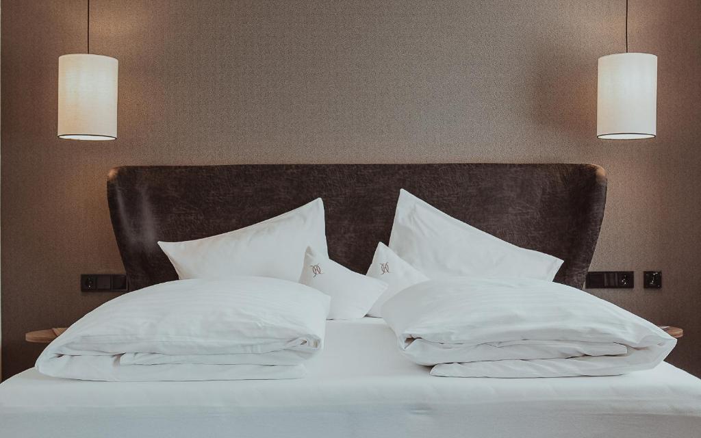 Mūsdienīgs guļamistabas interjers ar ērtu gultu, spilveniem un stilīgām lampām. Ģeometriska tekstūra uz sienas piešķir telpai eleganci.