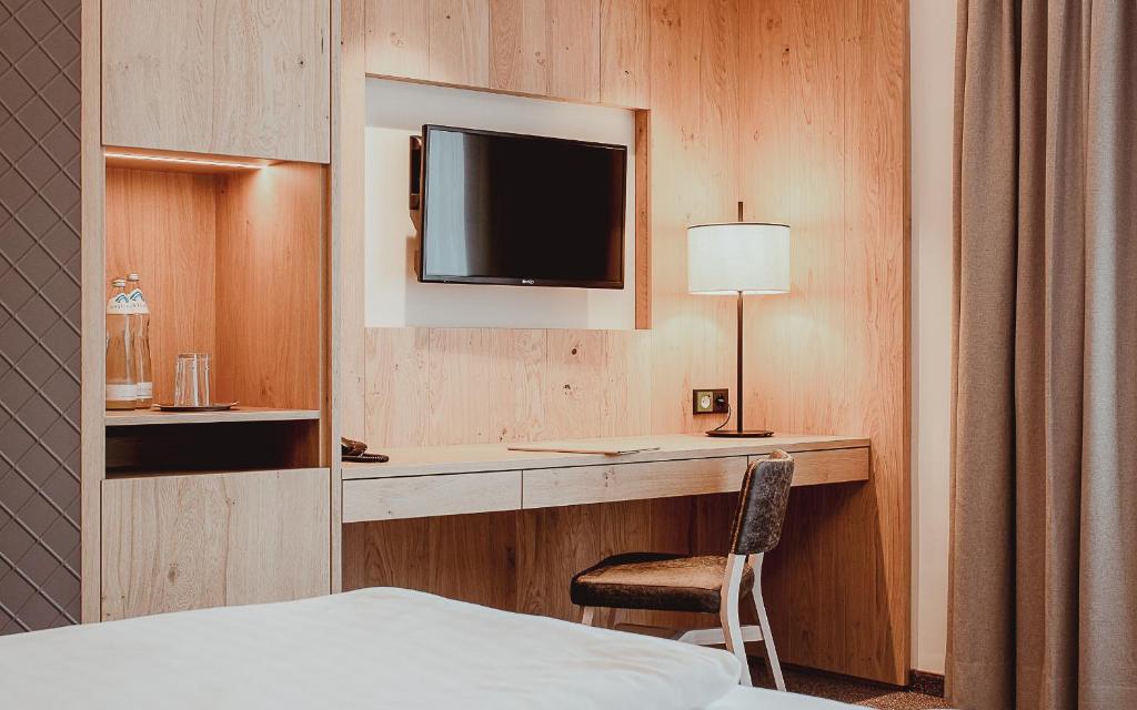 Mūsdienīgs viesnīcas numurs ar koka apdari, televizoru, rakstāmgaldu un lampu, radot ērtu un siltu atmosfēru. Ideāli piemērots darba un atpūtas vajadzībām.