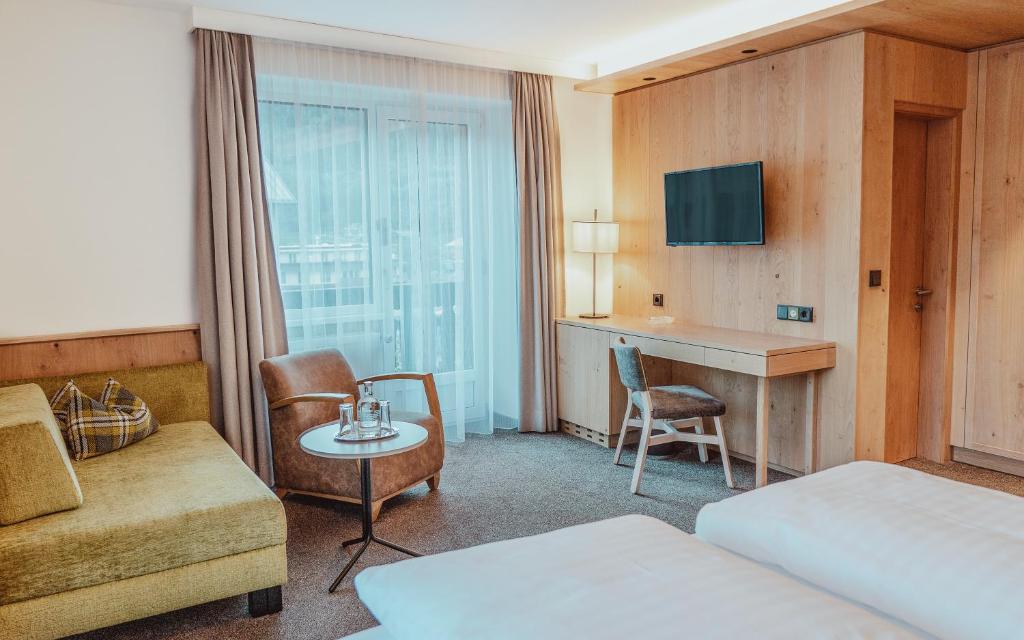 Mūsdienīgs viesnīcas numurs ar koka interjeru, ērtu dīvānu un rakstāmgaldu. Gaismas un logi rada mājīgu atmosfēru.