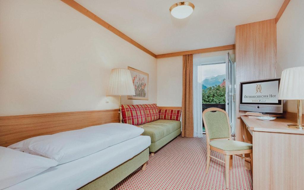 Mūsdienīga viesnīcas numura iekārtojums ar gultu, dīvānu un rakstāmgaldu, kā arī balkonu ar skatu uz dabu. Numurs ir gaišs un viesmīlīgs, nodrošinot komfortu un relaksāciju.