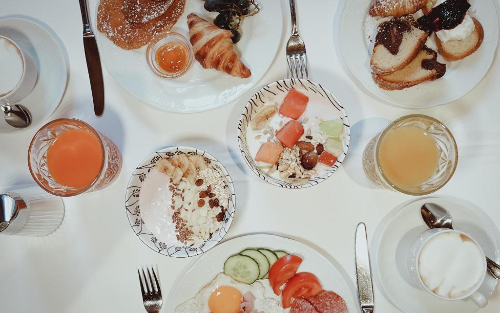 Brokastu galds ar dažādiem ēdieniem, tostarp maizēm, augļu salātiem un dzērieniem. Krāsaini un daudzveidīgi ēdieni, kas veidoti no veselīgām sastāvdaļām.