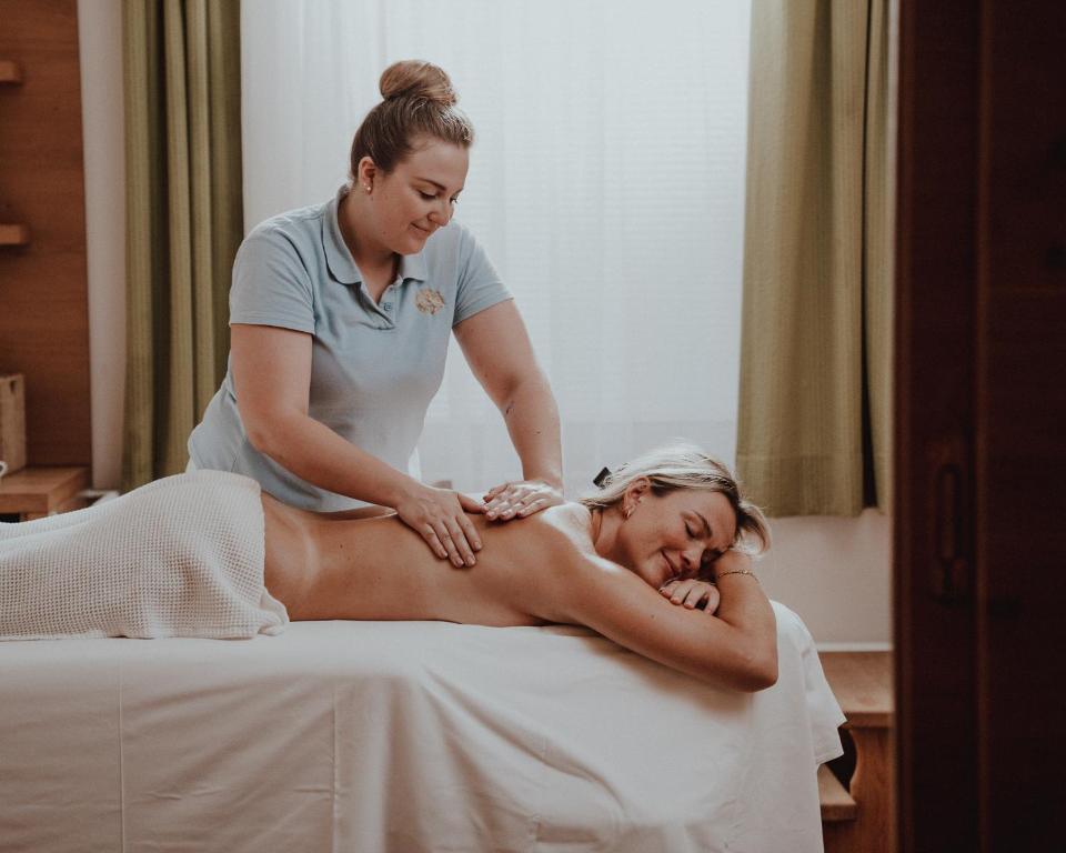 Masāžas sesija relaksējošā vidē, kur masieris strādā ar klienta muguru.