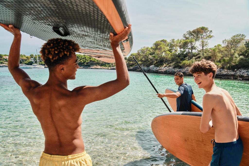 Jauni puiši, kas nodarbojas ar sērfošanu pie jūras, jautri un aktīvi pavadot laiku pludmalē.