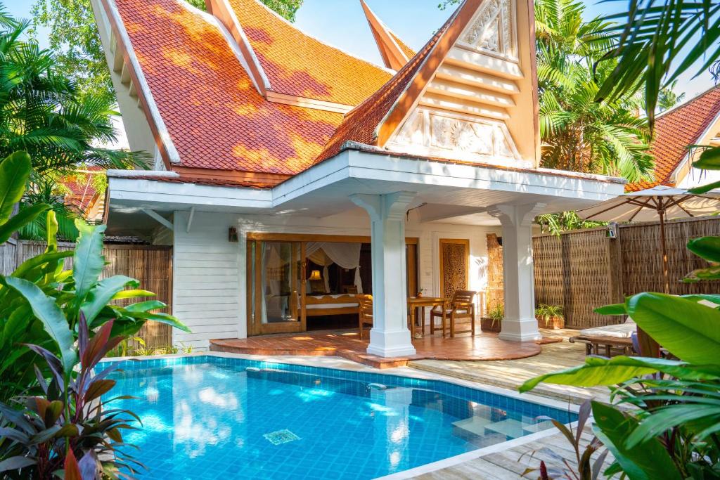Tropu stila villa ar sarkanu jumtu un privātu baseinu, ieskauta zaļumiem un augiem, radot mierīgu un relaksējošu atmosfēru. Ideāla vieta atpūtai un brīvā laika pavadīšanai.