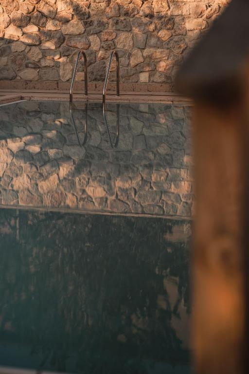 Mierīgas baseina atspulgs ar akmens sienu fonā, radot relaksējošu atmosfēru.
