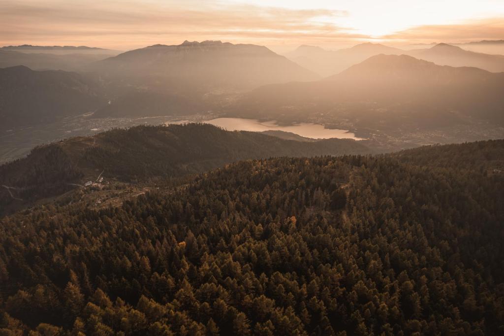 Apskate uz kalnu ainavu ar saulrietu, ar mežainiem pakalniem un ezeru apakšā. Mīksta gaisma piešķir skats mierīgu un noslēpumainu noskaņu.