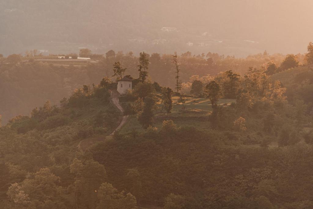 Kalna ainava ar mazu mājiņu un kokiem, saules gaismas apgaismota. Rudenīga atmosfēra ar siltiem toņiem.