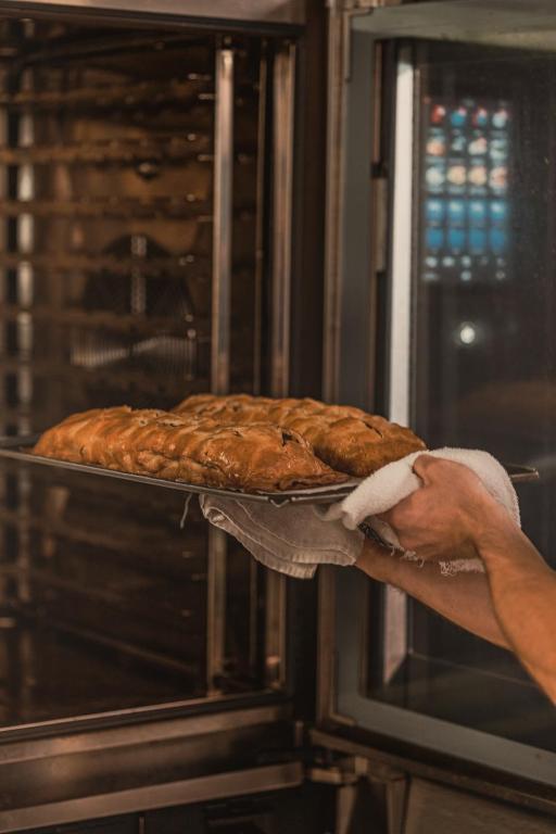 Svaigi cepti maizes izstrādājumi tiek izņemti no cepeškrāsns, turot tos uz cepešpannas.