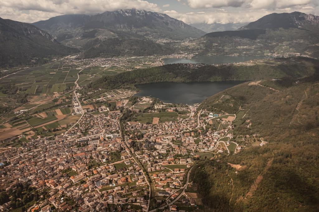 Ainava no augšas, kur redzama pilsēta, apkārt esošie laukumi un kalni, ar diviem ezeriem fonā. Krāšņs ainavas skats, kas attēlo dabu un cilvēku apdzīvotās teritorijas.